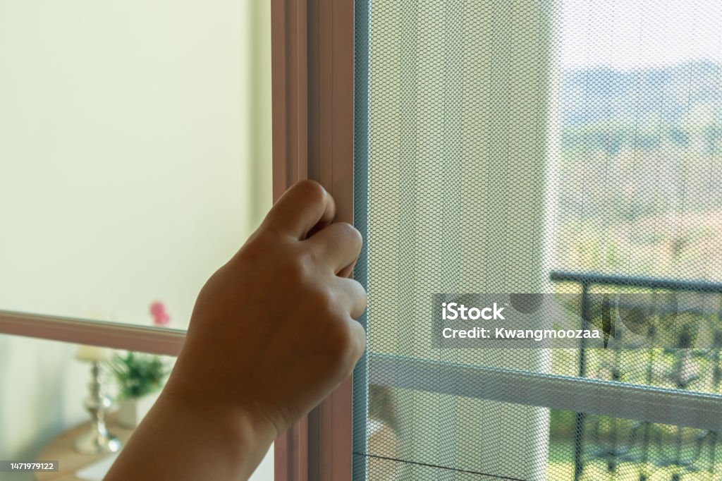 Hand hold pleated mosquito net wire screen handle on house window Mosquito Netting Stock Photo