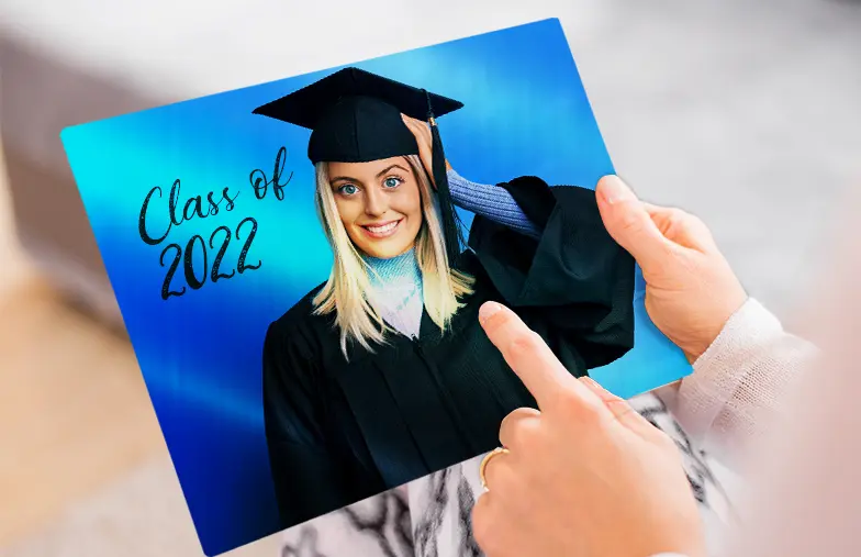 Stampa fotografica in metallo di Printerpix|Stampa fotografica in alluminio di una laurea|Piccola stampa in metallo quadrata di un uomo che si tuffa nel lago|Stampa fotografica in metallo di mamma e figlia su una libreria|Donna che posiziona una stampa in metallo di fidanzata e fidanzato sul muro|Tre stampe fotografiche in metallo di dimensioni miste