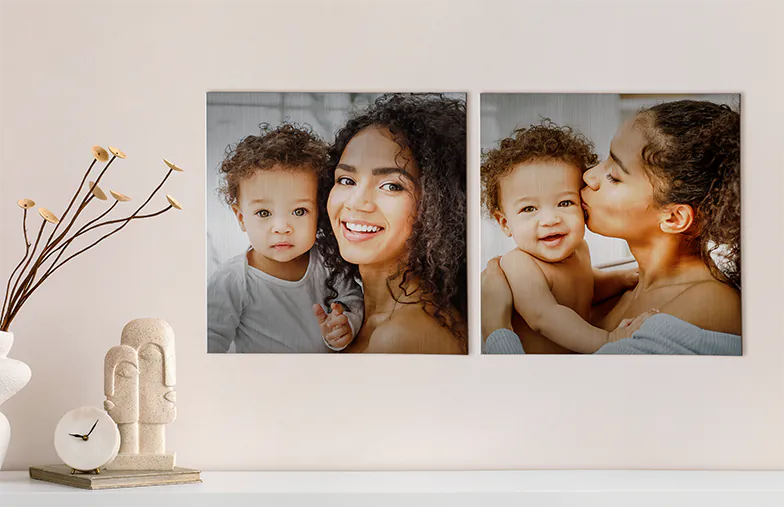 Stampe Fotografiche in Metallo|Stampe Fotografiche in Metallo|Piccola stampa metallica quadrata di un uomo che si tuffa nel lago|Stampa fotografica in metallo di mamma e figlia sulla libreria|Donna che posiziona una stampa metallica di fidanzata e fidanzato sul muro|Tre stampe fotografiche in metallo di dimensioni miste