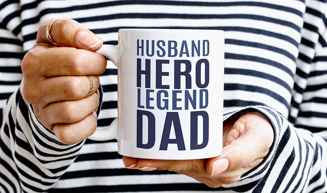 Mamma e bambino che tengono una tazza personalizzata con design a cartone animato di Printerpix con testo per papà