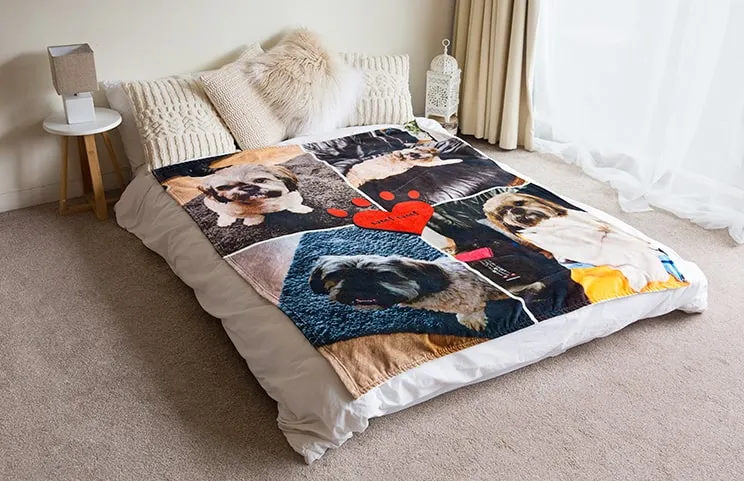 Una morbida coperta toque di vison di Printerpix con un design a collage di cani è stesa su un letto.
