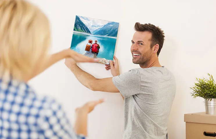 Uomo e donna che appendono una tela fotografica con una foto delle vacanze