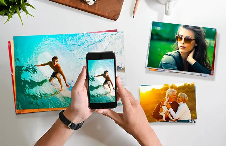Stampe fotografiche piccole, medie e grandi sul tavolo dal cellulare