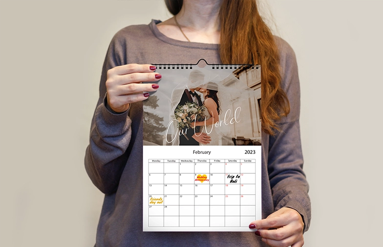 Donna che scrive su calendario da parete personalizzato A4 di printerpix con foto a tema natalizio