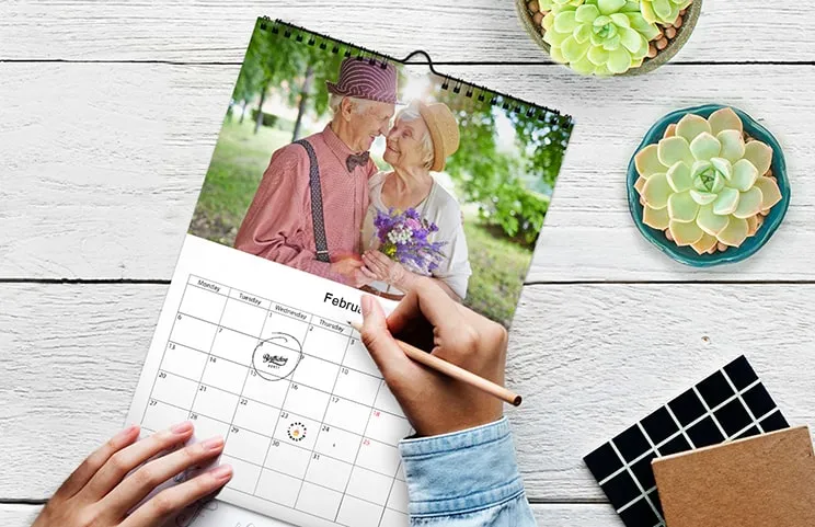 Donna che scrive su calendario da parete personalizzato A4 di printerpix con foto a tema natalizio