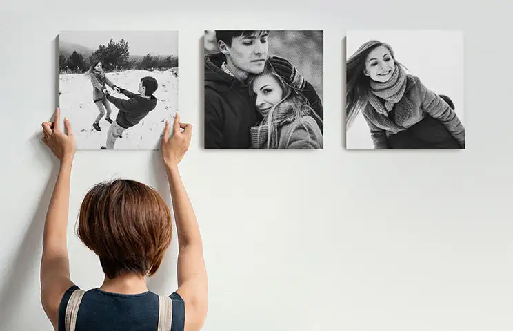 Donna che appende tre tele fotografiche di famiglia in bianco e nero