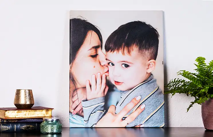 madre che bacia affettuosamente il suo piccolo figlio su una stampa su tela
