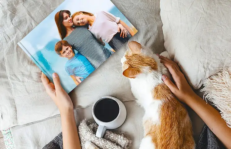 Animale domestico e donna che guardano un libro fotografico di famiglia personalizzato con design su misura