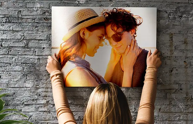 Donna che posiziona una stampa in metallo di fidanzata e fidanzato sul muro