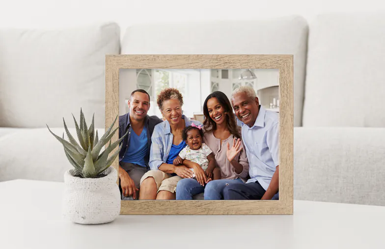 Foto di famiglia personalizzata: tre generazioni che sorridono insieme in una casa luminosa e ariosa. Conserva i tuoi ricordi!