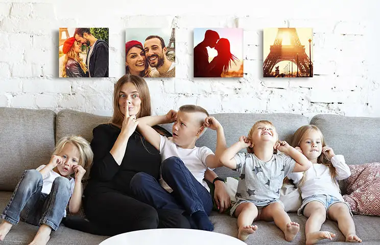 Mamma e quattro bambini piccoli seduti sul divano davanti a quattro tele fotografiche